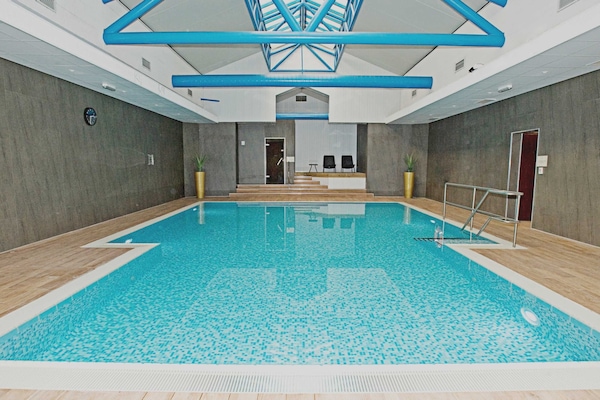 Een binnenzwembad, ligstoelen bij het zwembad