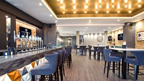 A modern bar area with a long counter, multiple bar stools, and a variety of bar tools.