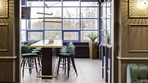 A modern kitchen with a large island, bar stools, and a view through large windows.