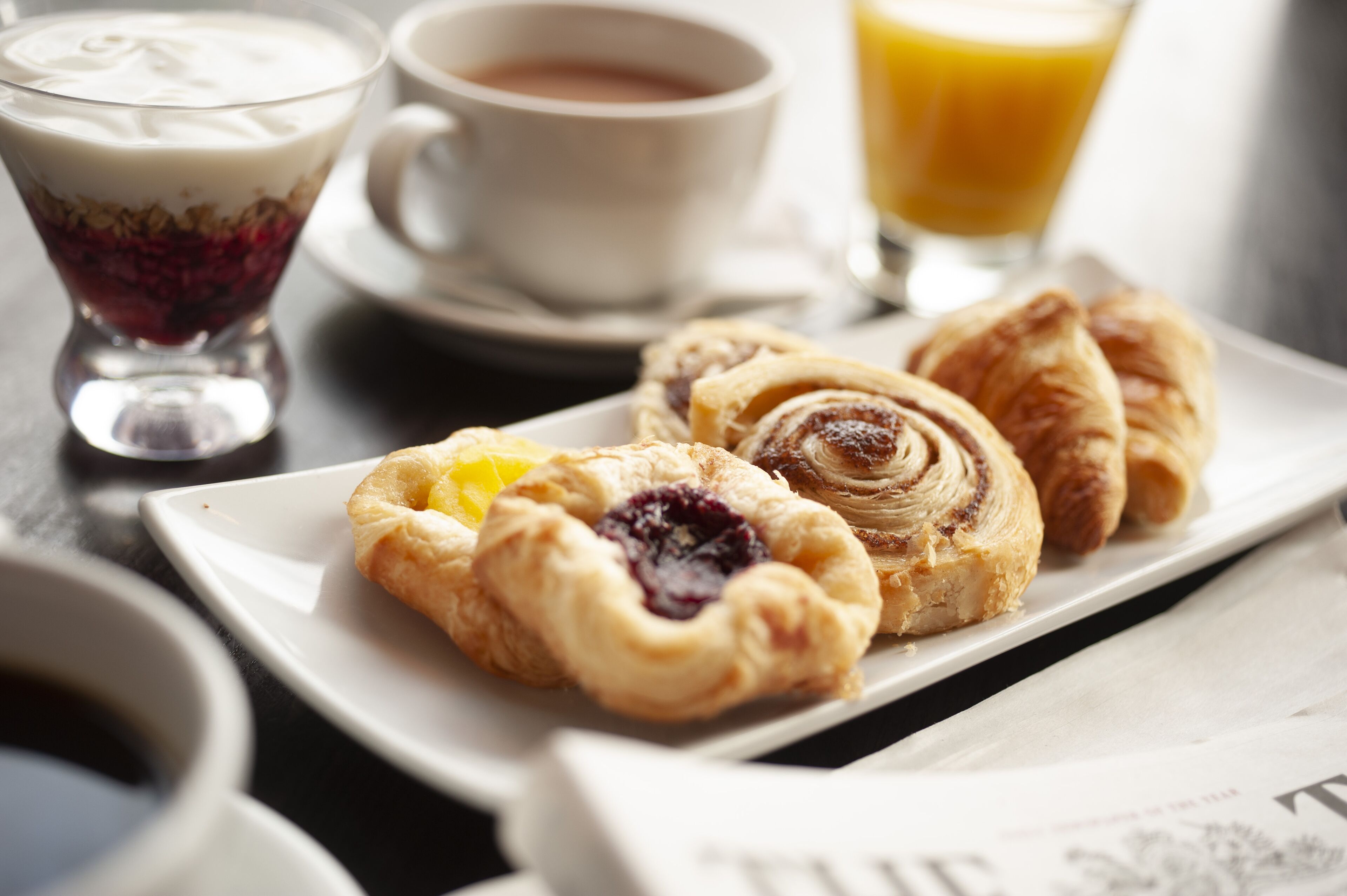A breakfast setting with pastries, a cup of coffee, and a glass of orange juice.