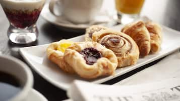 A breakfast setting with pastries, a cup of coffee, and a glass of orange juice.