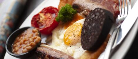 A plate of breakfast food including eggs, sausages, mushrooms, and beans.