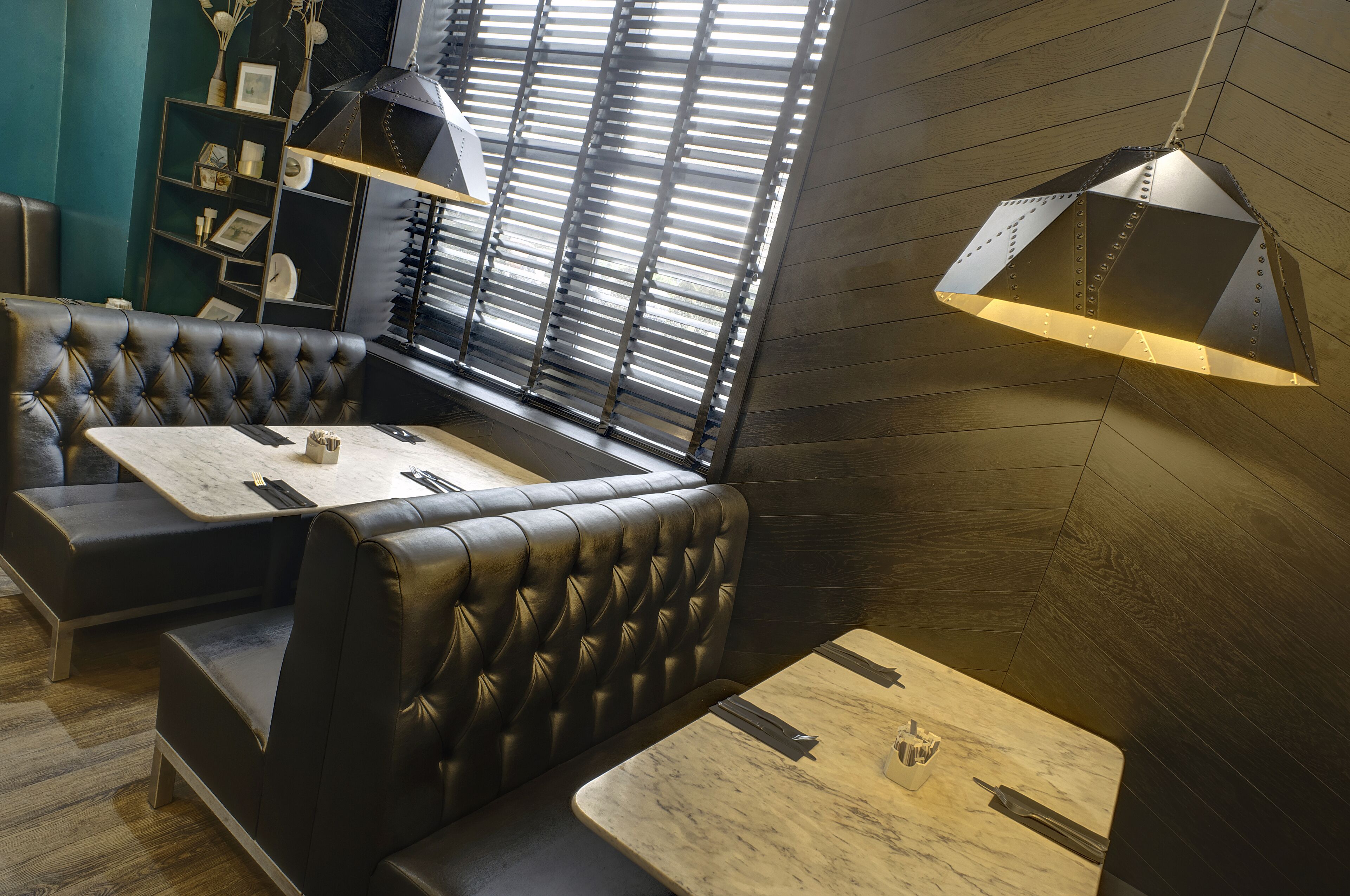 A restaurant interior with leather booths, wooden tables, and a large window with blinds.