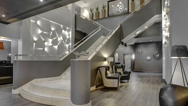 A modern interior with a central staircase, seating area, and decorative wall elements.