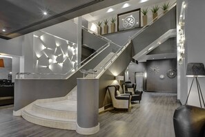 A modern interior with a central staircase, seating area, and decorative wall elements.