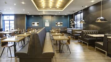 A modern restaurant with long booths, wooden tables, and pendant lighting.