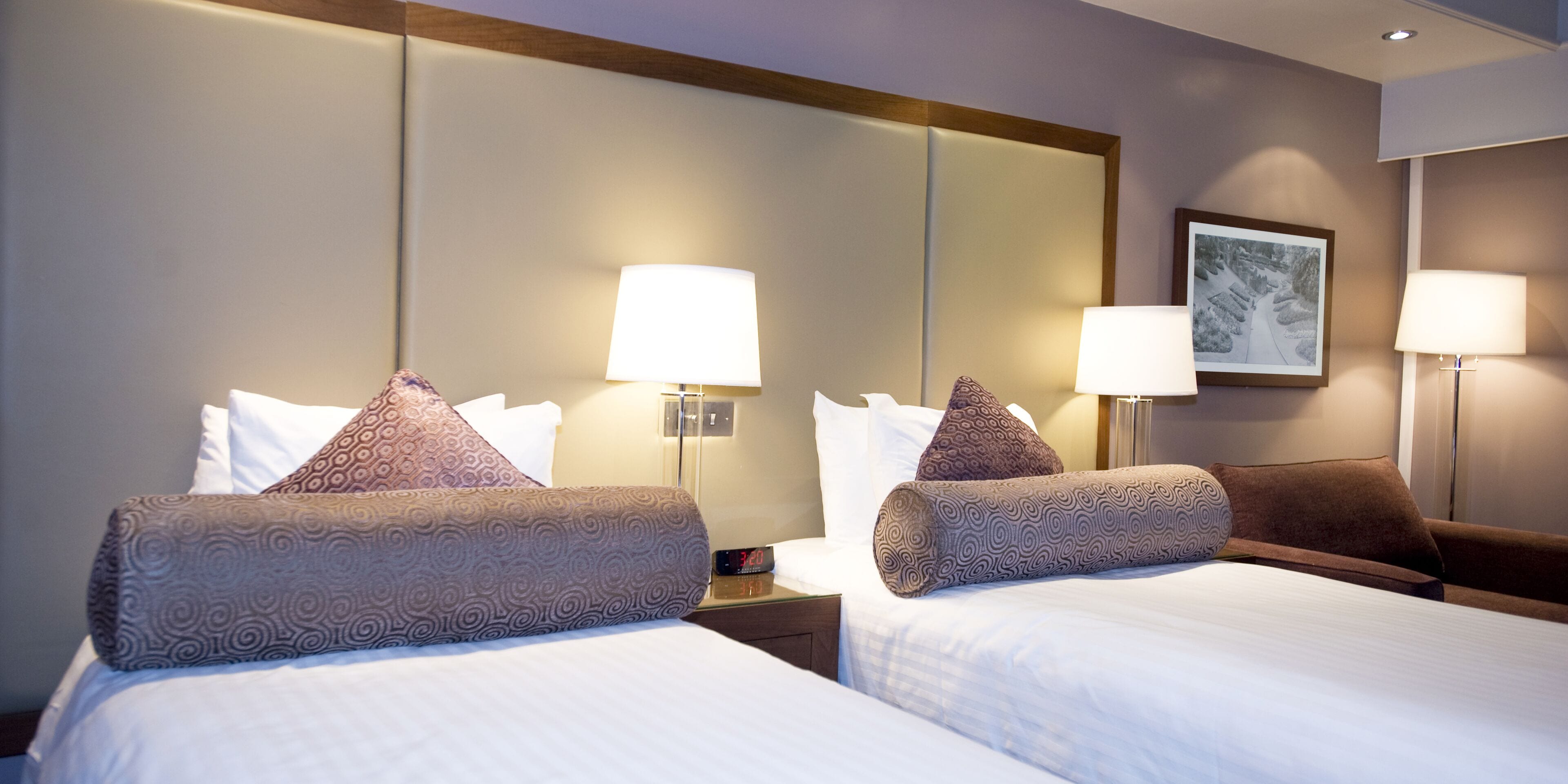 Une chambre d’hôtel avec deux lits, chacun agrémenté d’oreillers à motifs et de lampes de chevet.