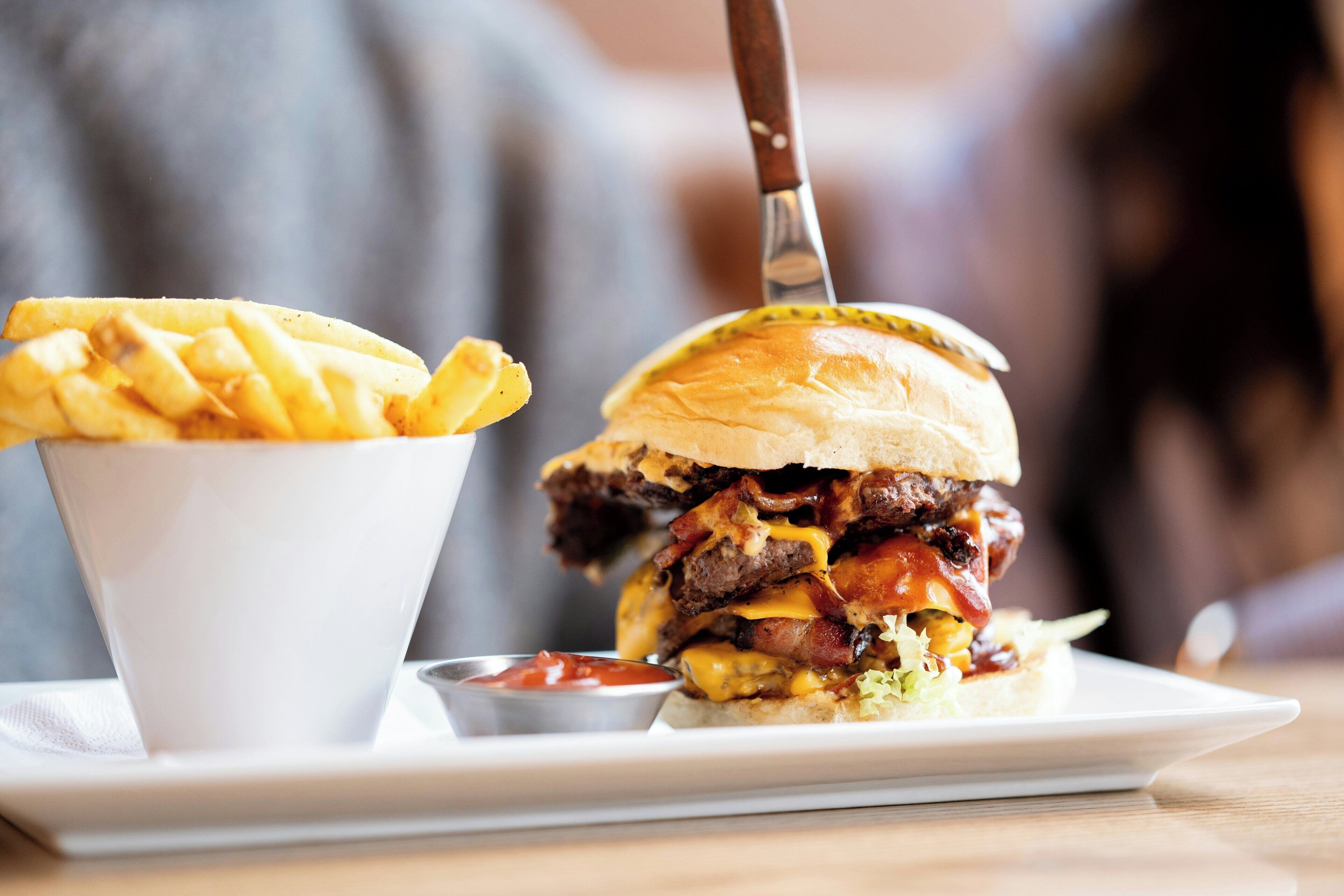 A burger with fries and ketchup on a white plate.