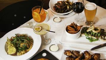 A dining table with various dishes, including pizza, wings, and a salad.