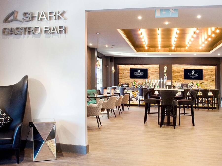 A modern bar with a wooden ceiling and a sign reading "Shark Gastro Bar".