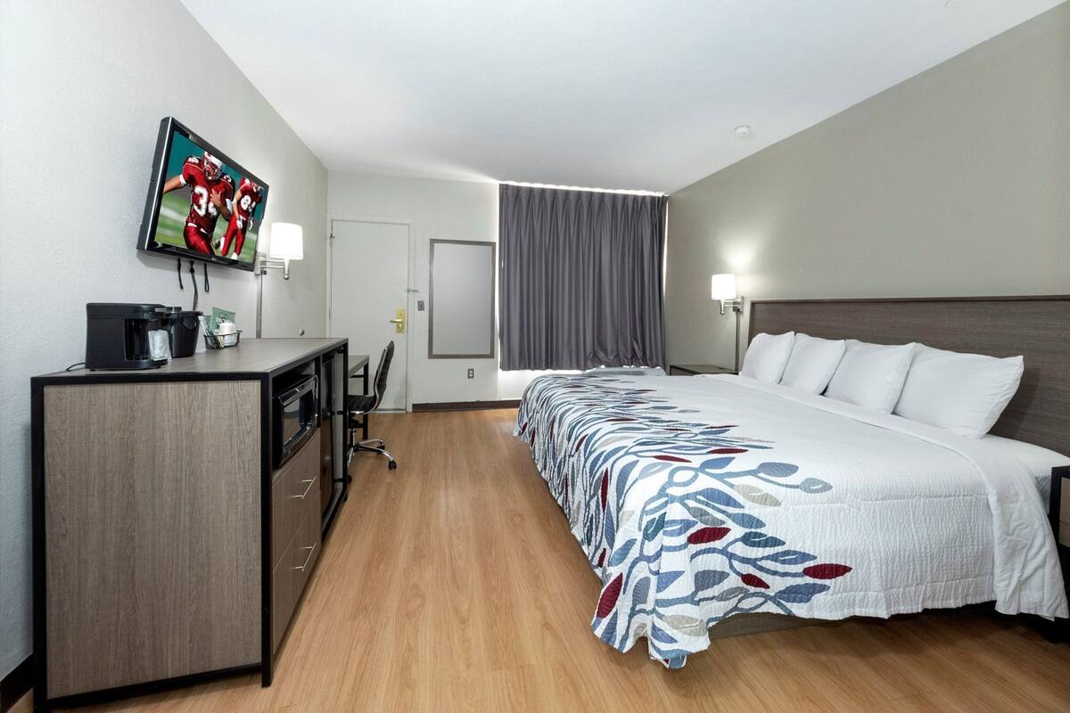 Una camera d'albergo con un letto, una scrivania con una macchina del caffè, una TV e una porta.