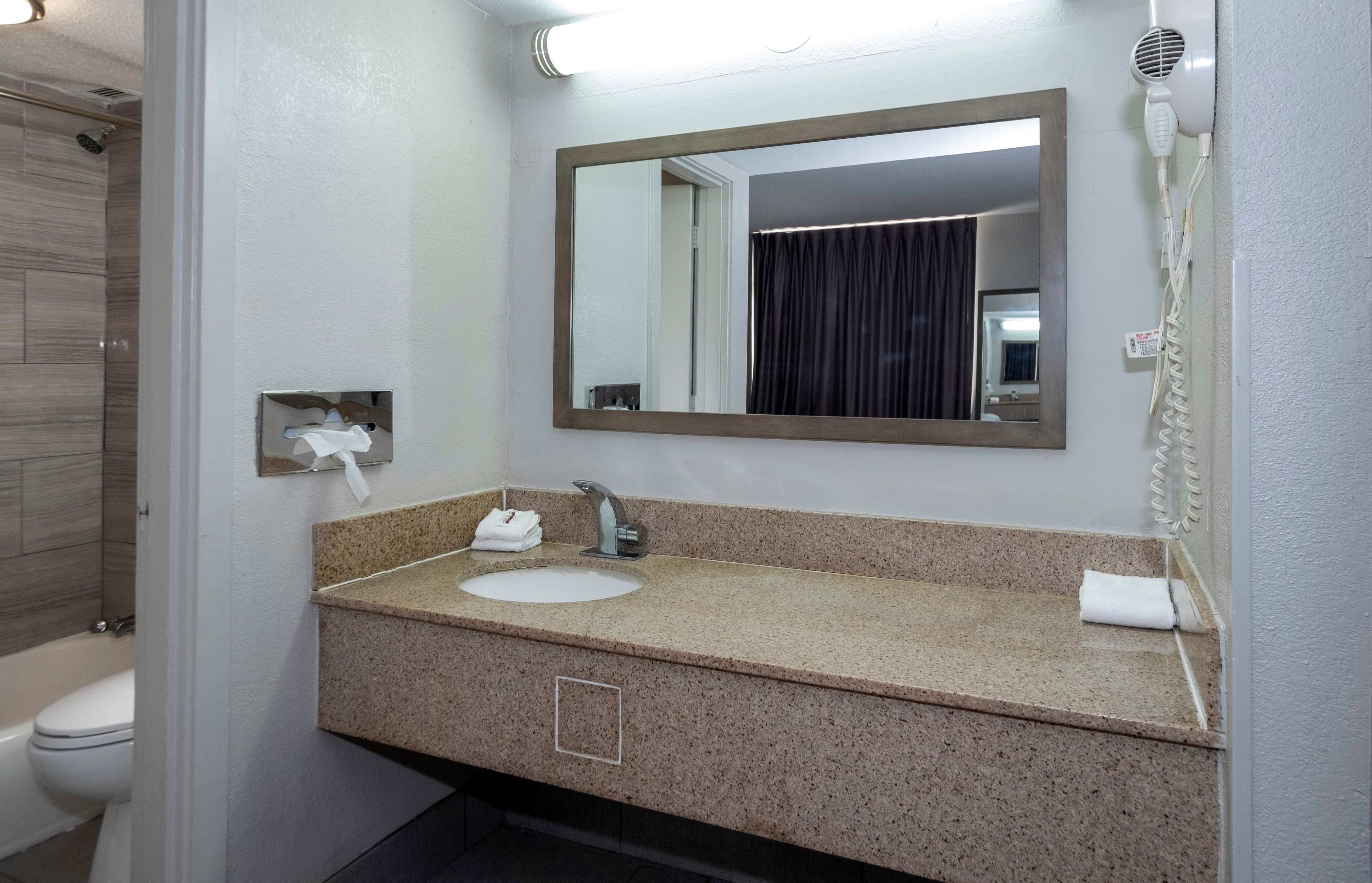 Une salle de bain équipée d’un lavabo, d’un miroir et d’un sèche-cheveux.