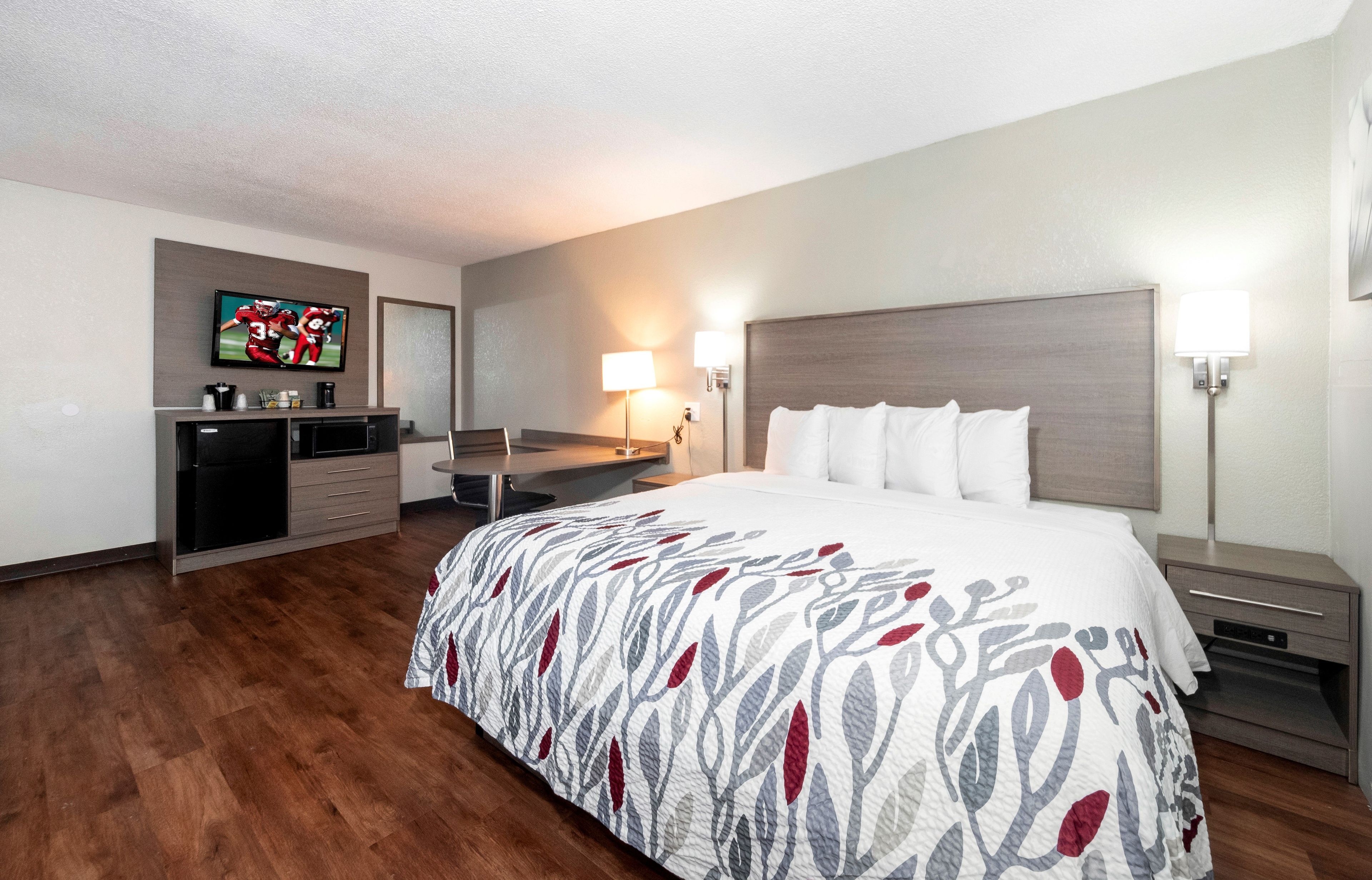 Ein Hotelzimmer mit Bett, Schreibtisch, Fernseher und Spiegel.