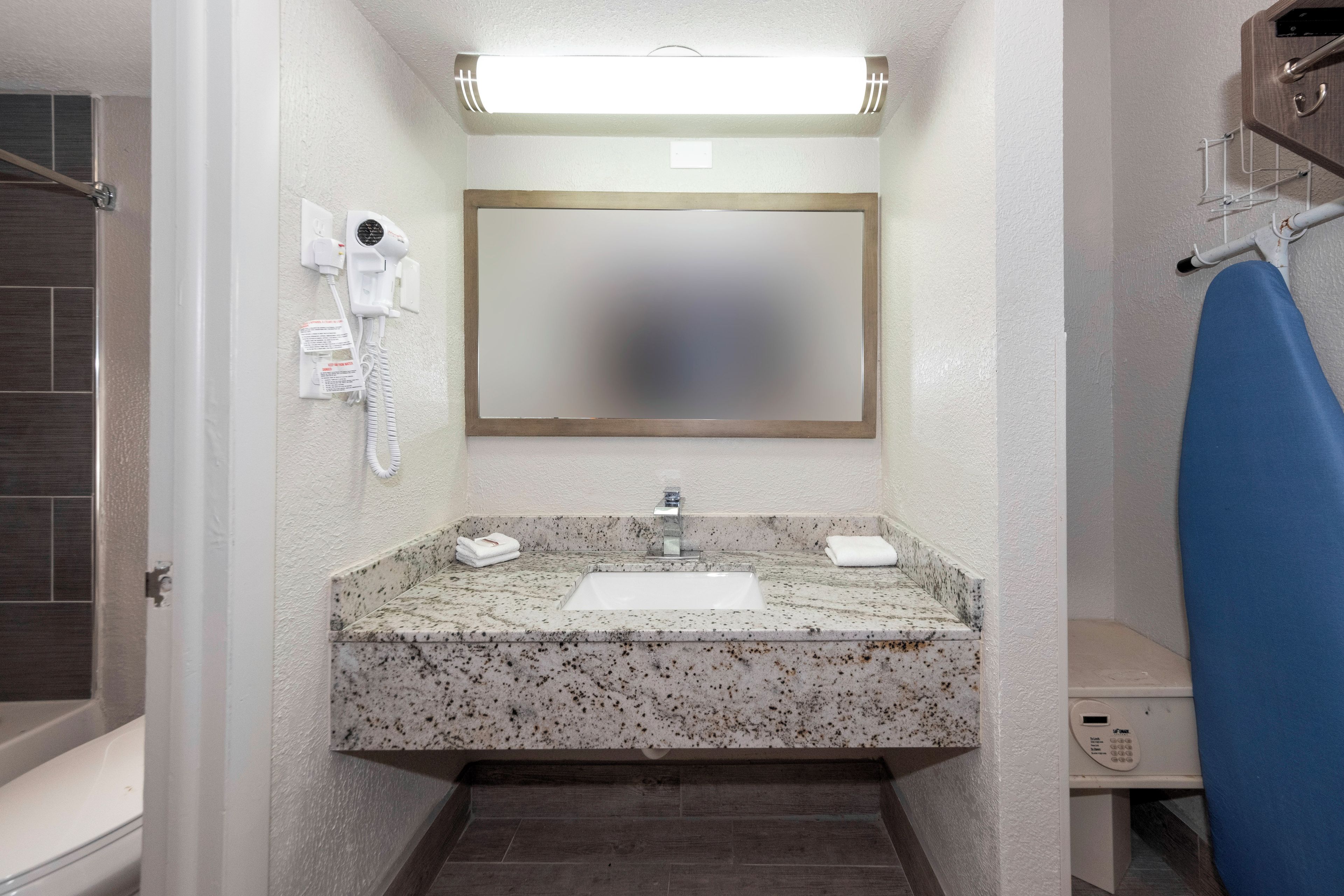 A bathroom with a marble sink, a mirror, a hairdryer, and a towel rack.