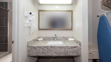 A bathroom with a marble sink, a mirror, a hairdryer, and a towel rack.
