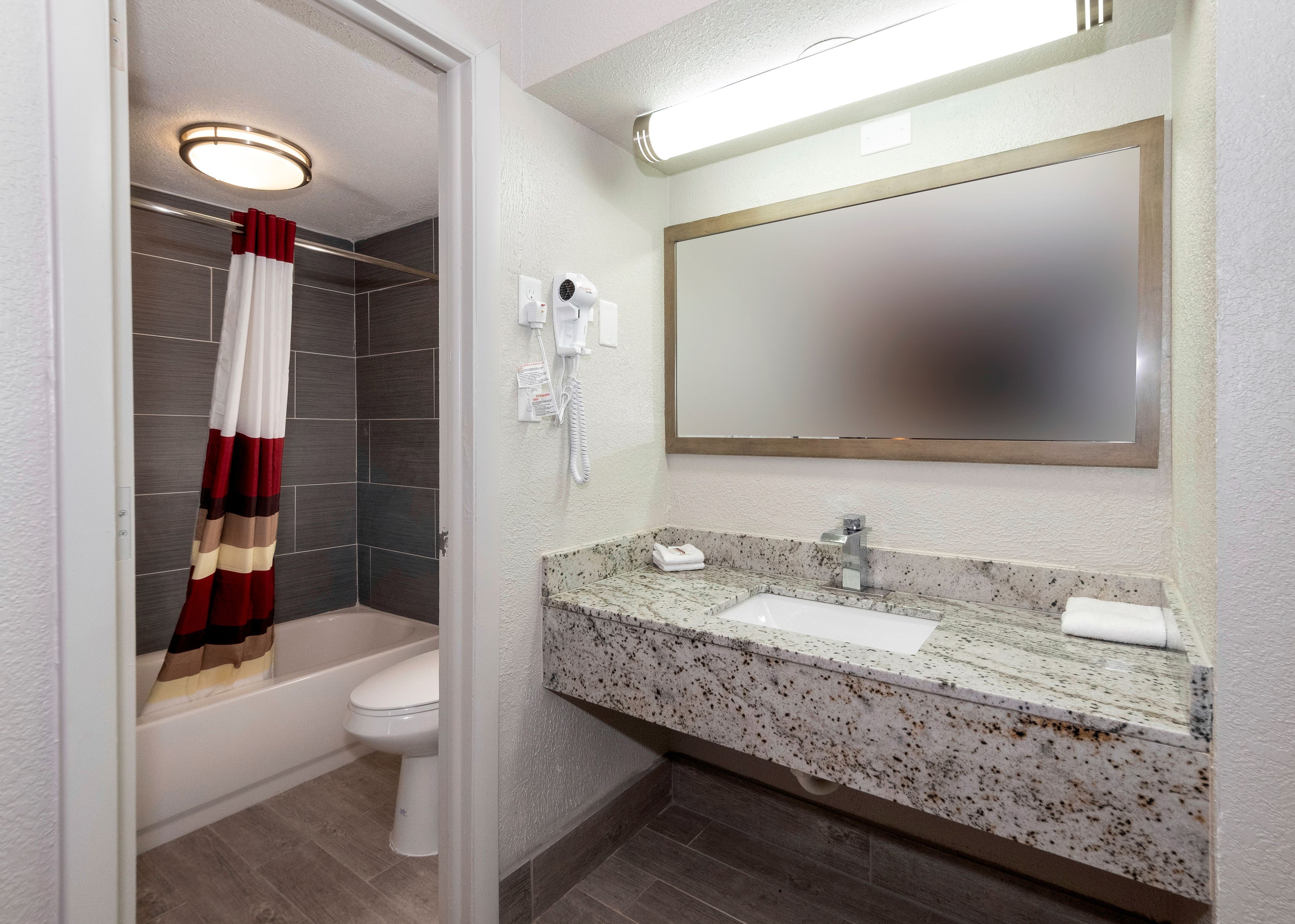 Ein Badezimmer mit Dusche, Toilette, Waschbecken und Spiegel.