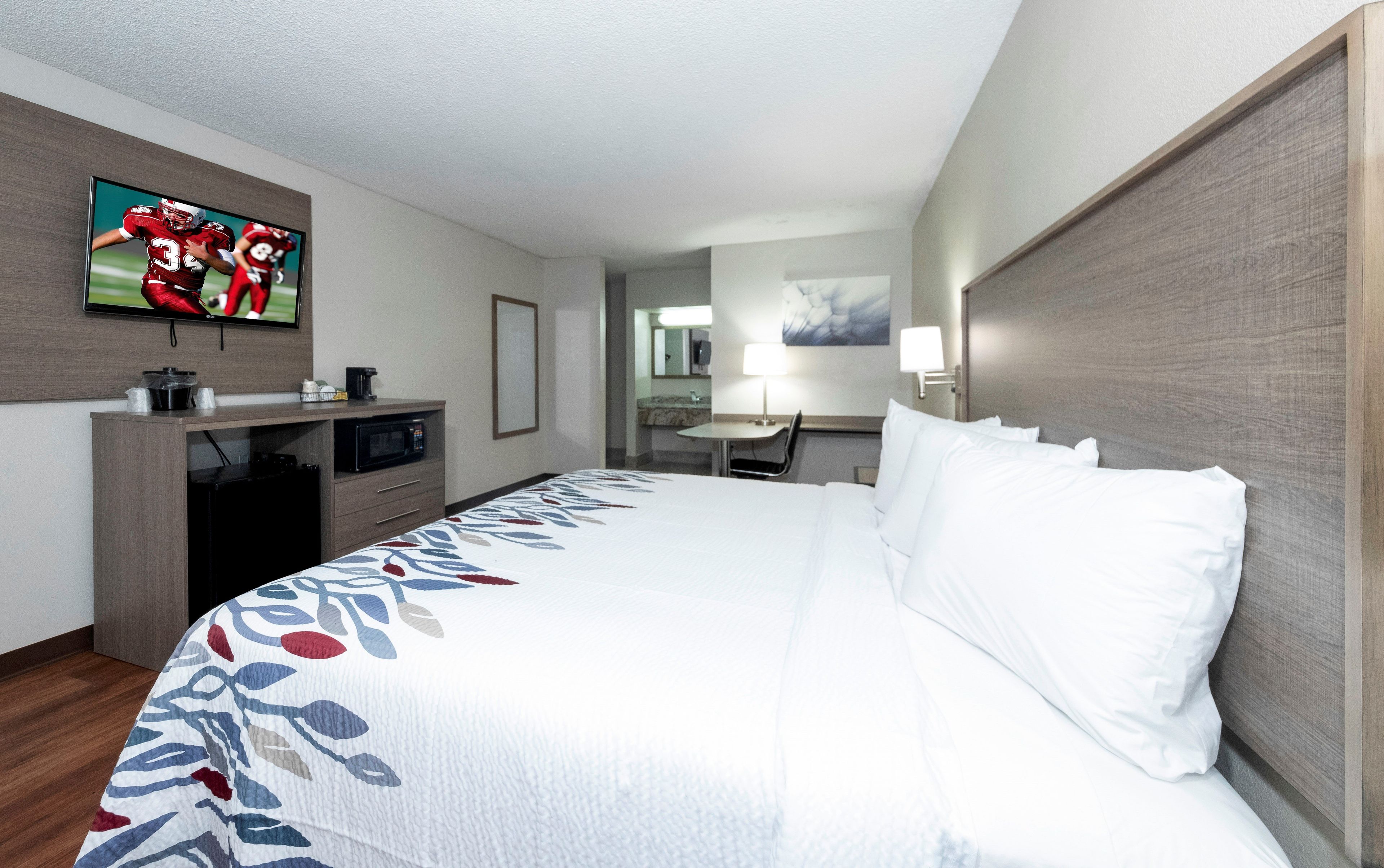 A hotel room with a bed, a television, a desk, and a chair.