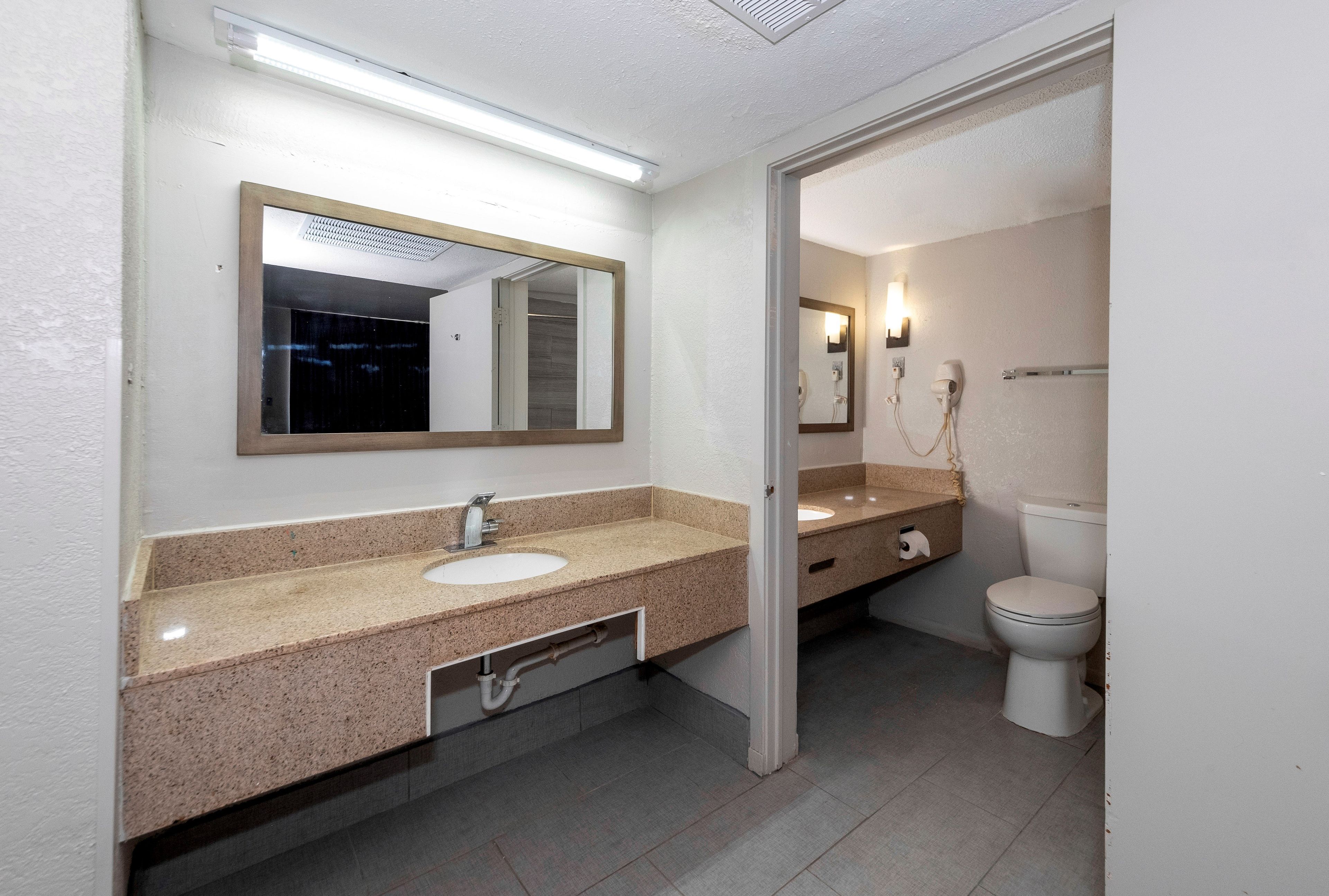 A bathroom with a sink, mirror, toilet, and towel rack.