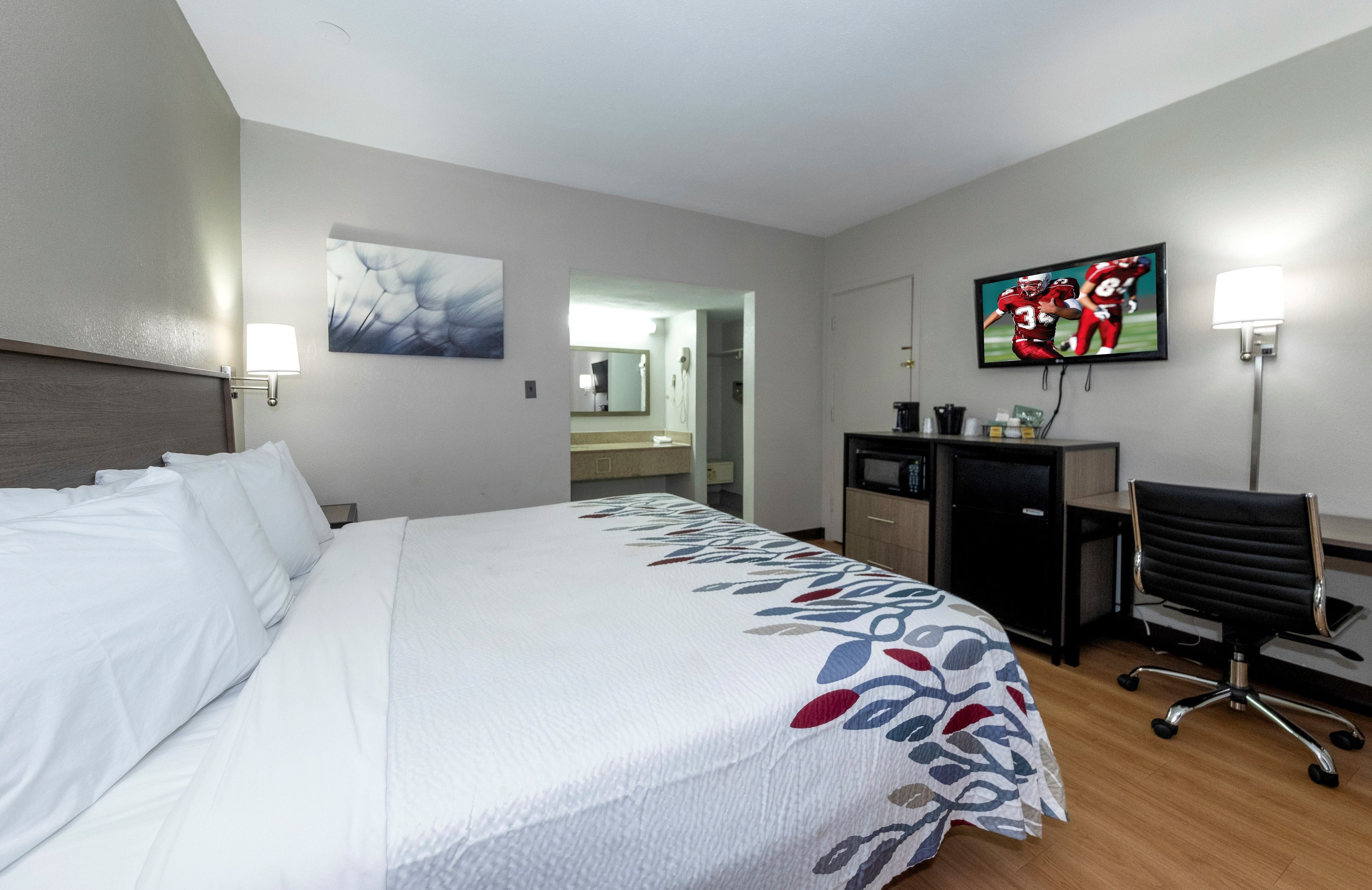 Habitación de hotel con cama, escritorio, silla, televisor y obras de arte.