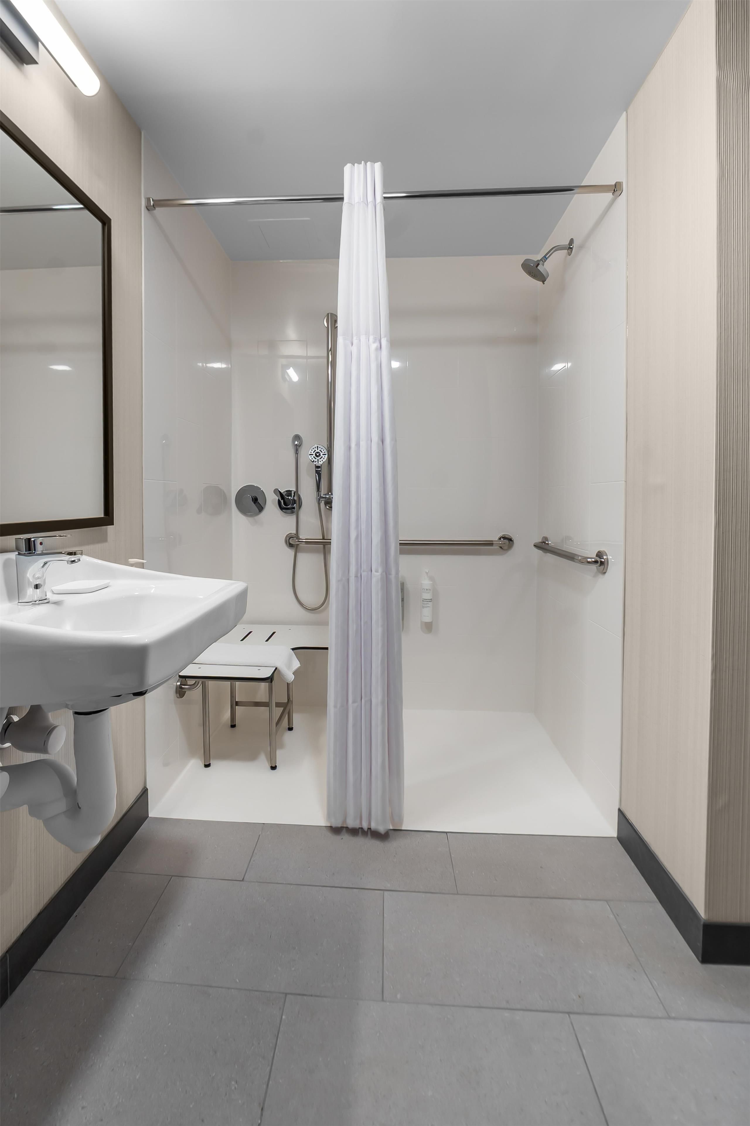 A modern bathroom with a shower, a sink, and a mirror.