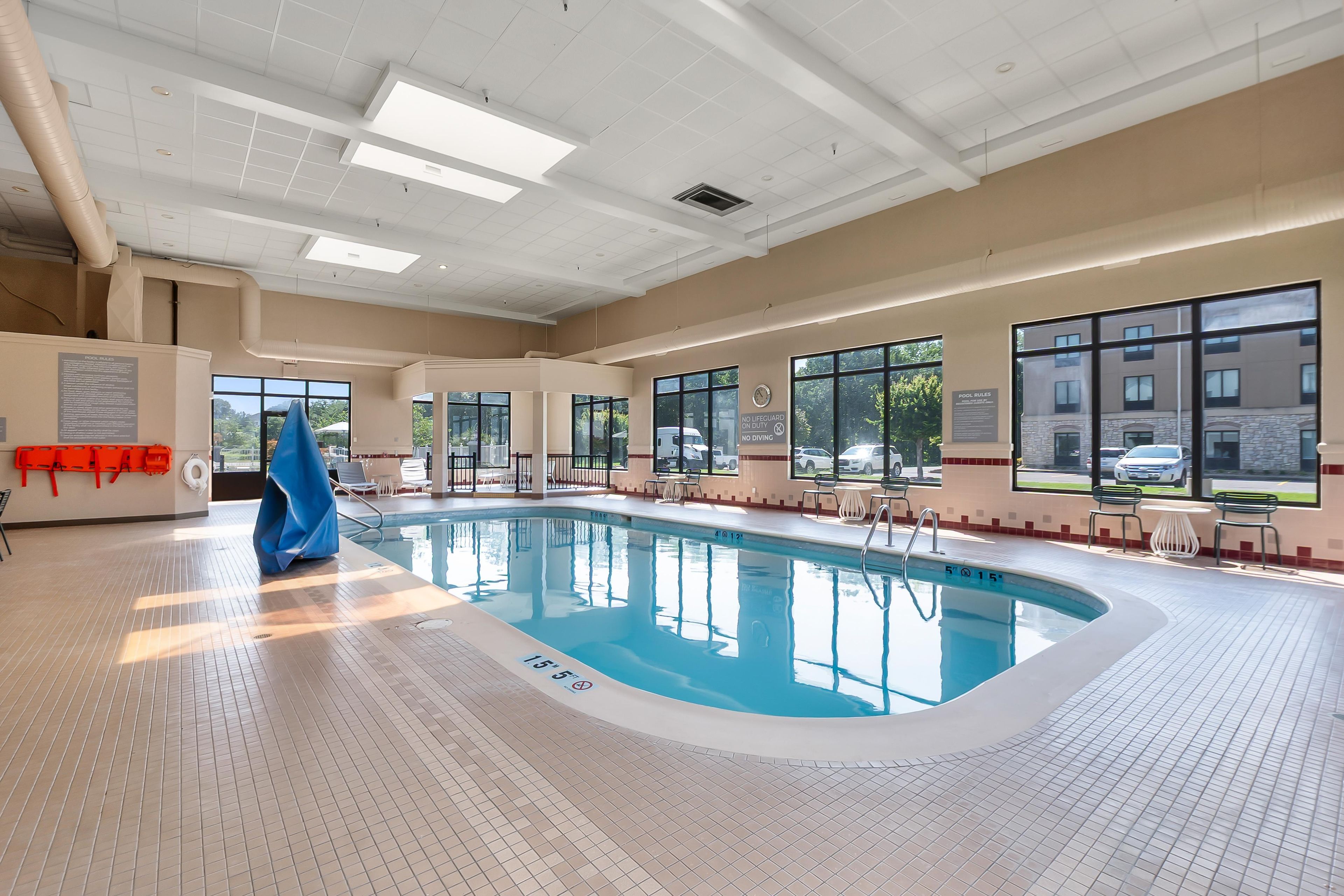Una piscina interior con agua cristalina, líneas de profundidad marcadas y señalización de seguridad.