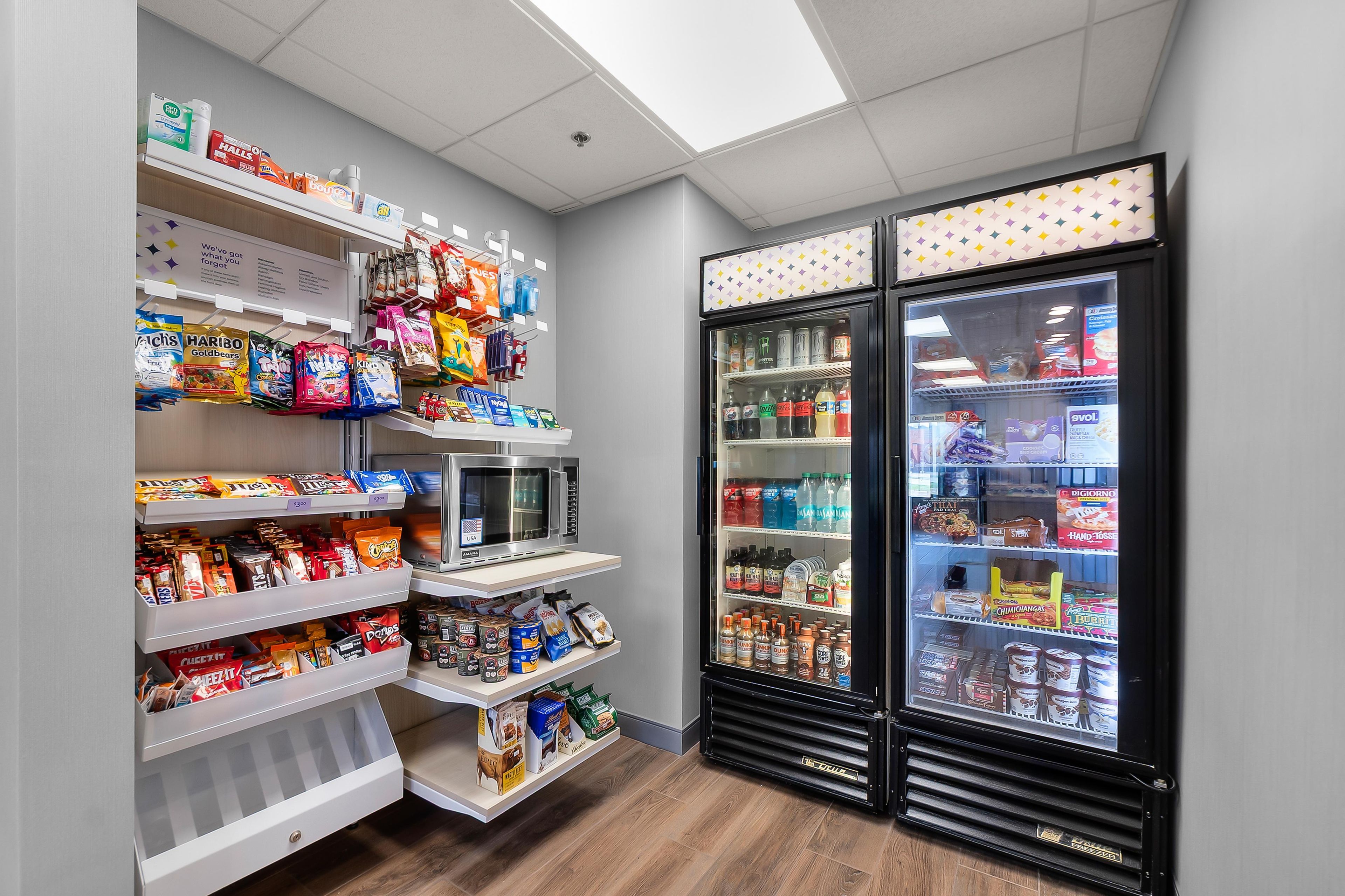 A snack and beverage vending area with various snacks, drinks, and a microwave.