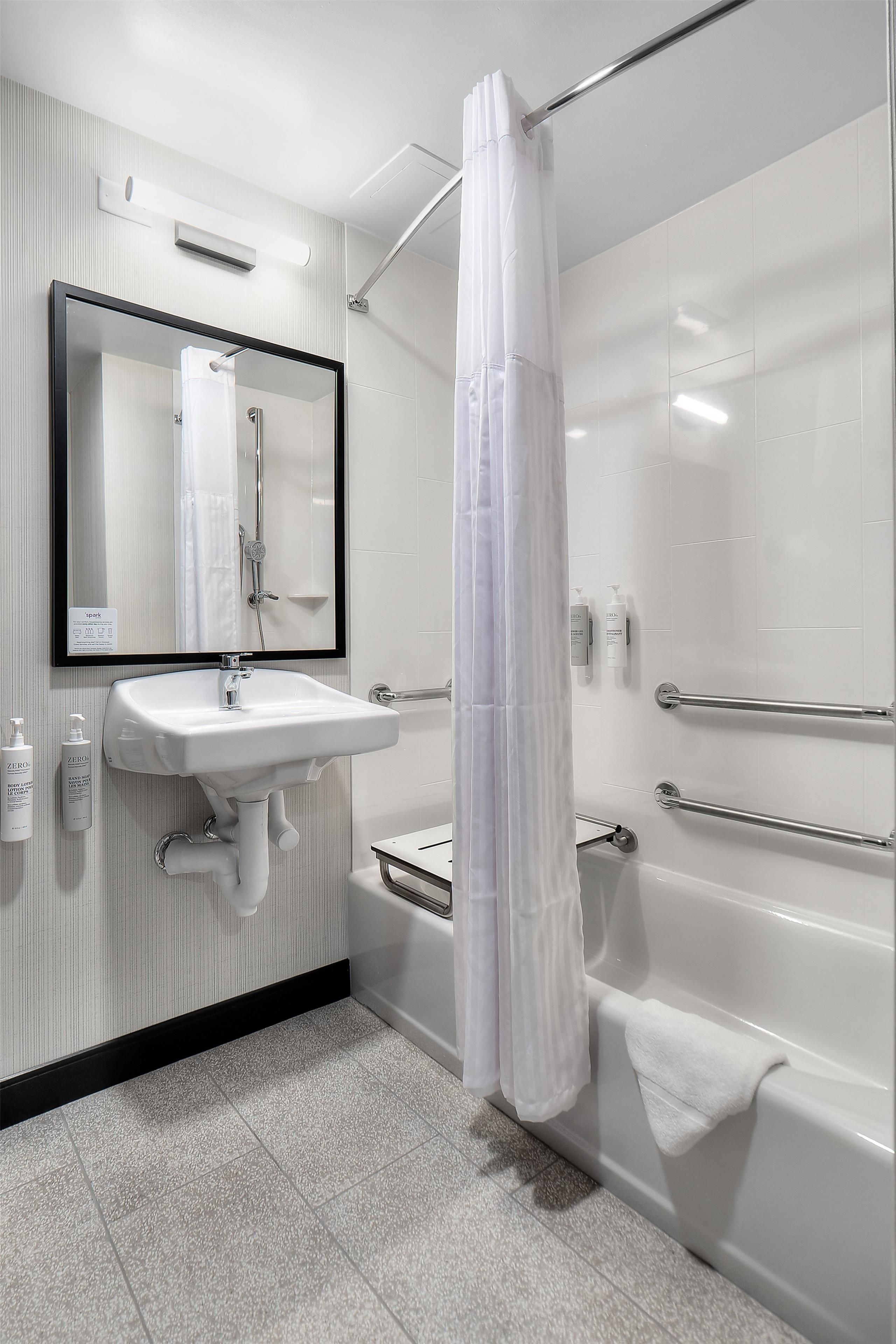 A modern bathroom with a white sink, mirror, and shower area.