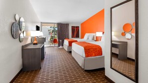 A hotel room with two beds, a desk, a chair, and a large mirror. - Howard Johnson by Wyndham Vero Beach / Downtown (Vero Beach)