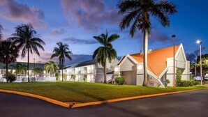 A modern hotel with a unique architectural design, featuring a sloped roof and a well-maintained lawn. - Howard Johnson by Wyndham Vero Beach / Downtown (Vero Beach)