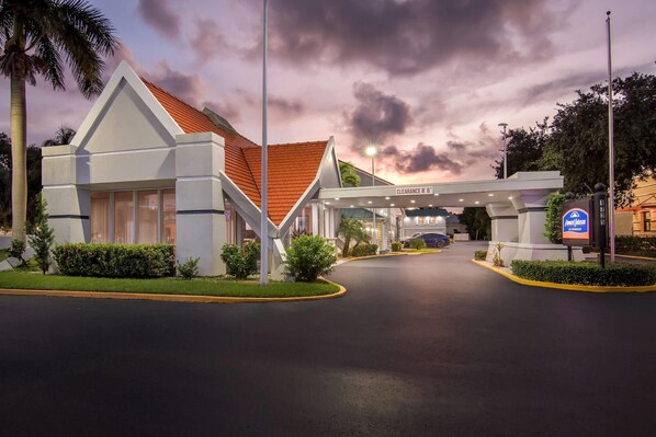 A hotel entrance with a clearway sign, a parking sign, and a flagpole.