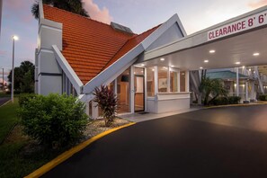 A modern building with a sloped roof and a clear sign indicating a clearance height of 8' 6". - Howard Johnson by Wyndham Vero Beach / Downtown (Vero Beach)