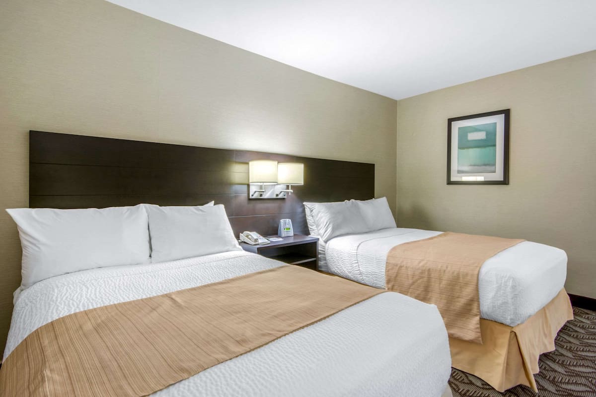 Ein Hotelzimmer mit zwei Betten, einem Nachttisch mit Telefon und einem gerahmten Bild an der Wand.