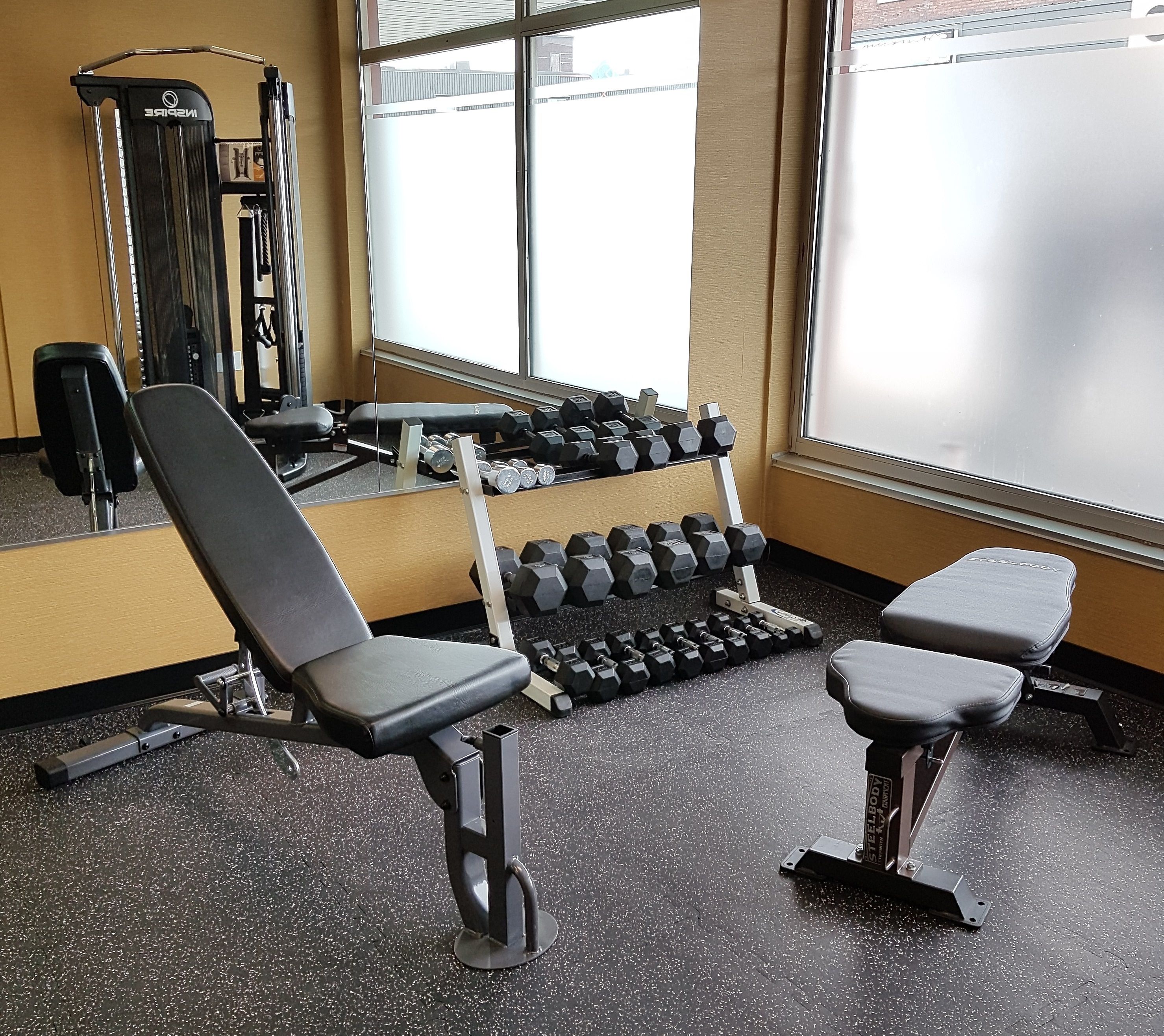 A gym with benches, dumbbells, and weight machines.