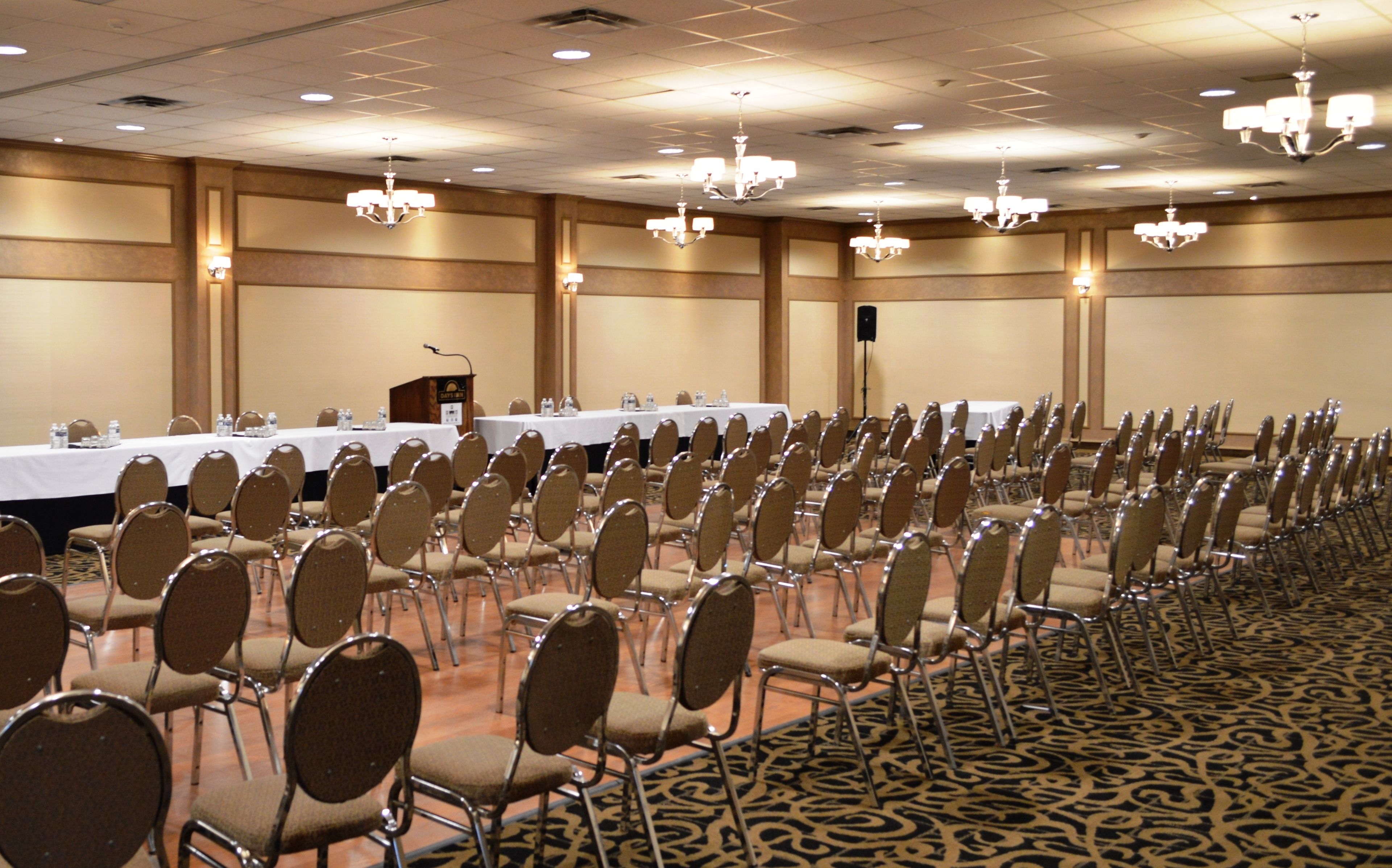 A conference room with rows of chairs, tables, and a podium.