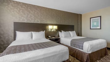 Ein Hotelzimmer mit zwei Betten, einem Nachttisch mit Lampe und einem gerahmten Bild an der Wand.