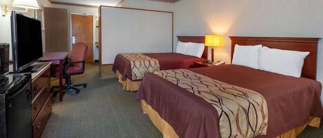 A hotel room with two beds, a desk with a television, a chair, and a desk lamp.