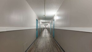 Um corredor comprido e estreito com piso de madeira e paredes claras.