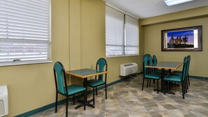 Uma área de refeições com mesa e cadeiras, um aparelho de ar condicionado e um quadro pendurado na parede.