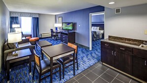 Une chambre d’hôtel comprenant un coin repas, une télévision, un canapé et une kitchenette.