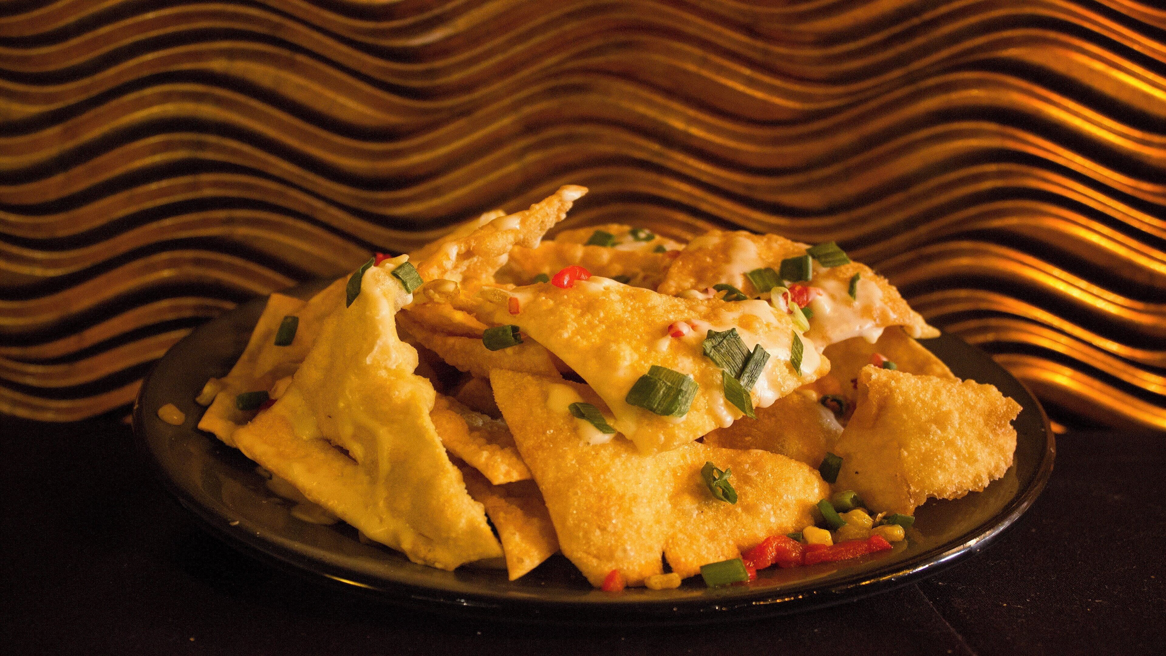 A plate of nachos with cheese and green onions.