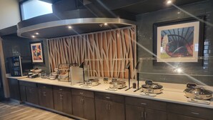 Uma cozinha moderna com geladeira embutida, espaço para café e diversos balcões de exposição de alimentos.