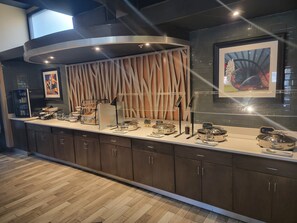 A modern kitchen with a built-in refrigerator, a coffee station, and a variety of food display cases.