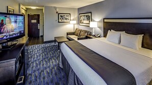 Une chambre d’hôtel avec un grand lit, un bureau avec une télévision, un canapé et une lampe.