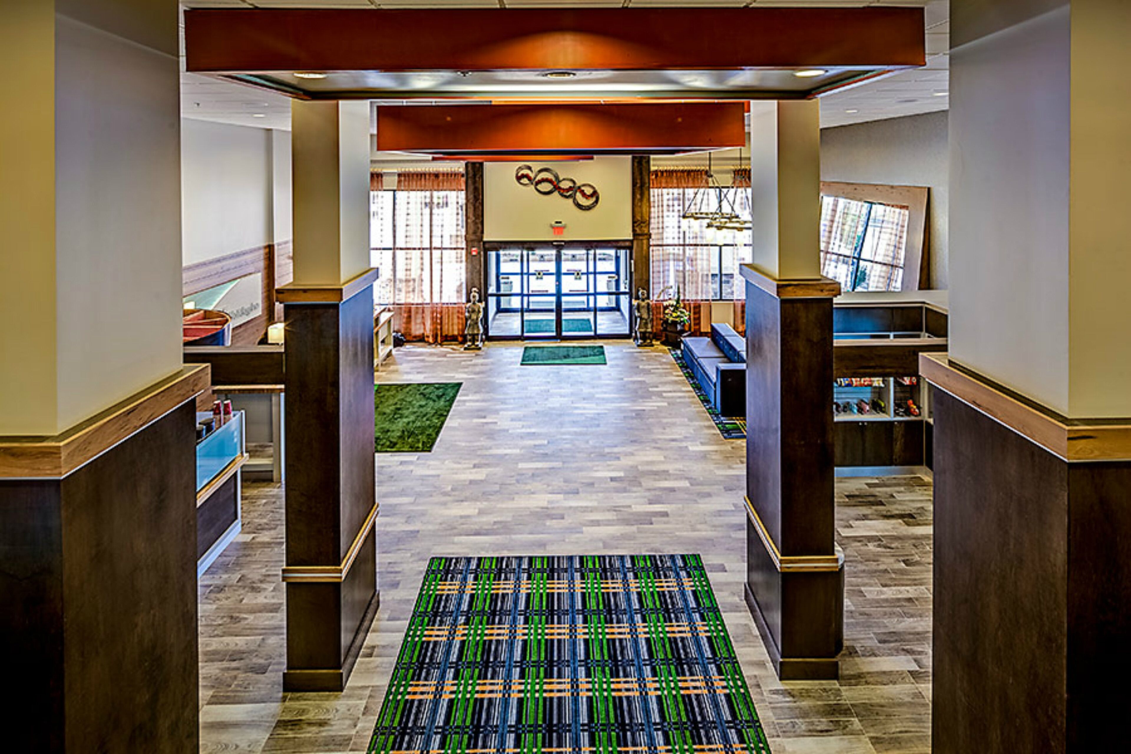 A hotel lobby with a central seating area, a reception desk, and a large window.