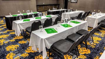 A conference room with multiple tables, each with chairs, glasses, and green placemats.
