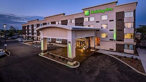 Um hotel Holiday Inn com design moderno, apresentando uma entrada destacada e um estacionamento.