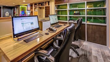A modern office space with two desktop computers, a printer, and leather chairs.