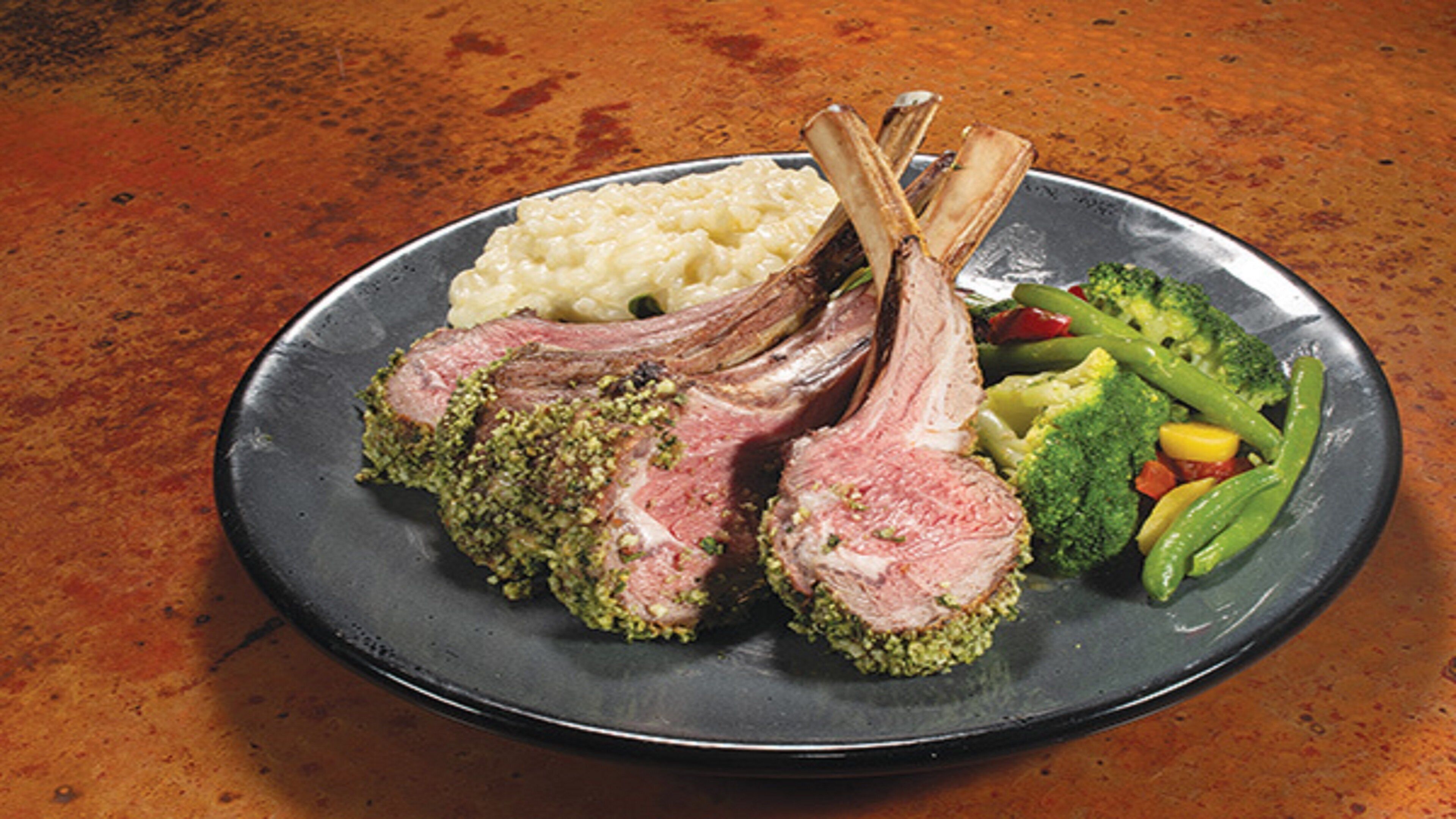 A plate with lamb chops, mashed potatoes, and steamed vegetables.