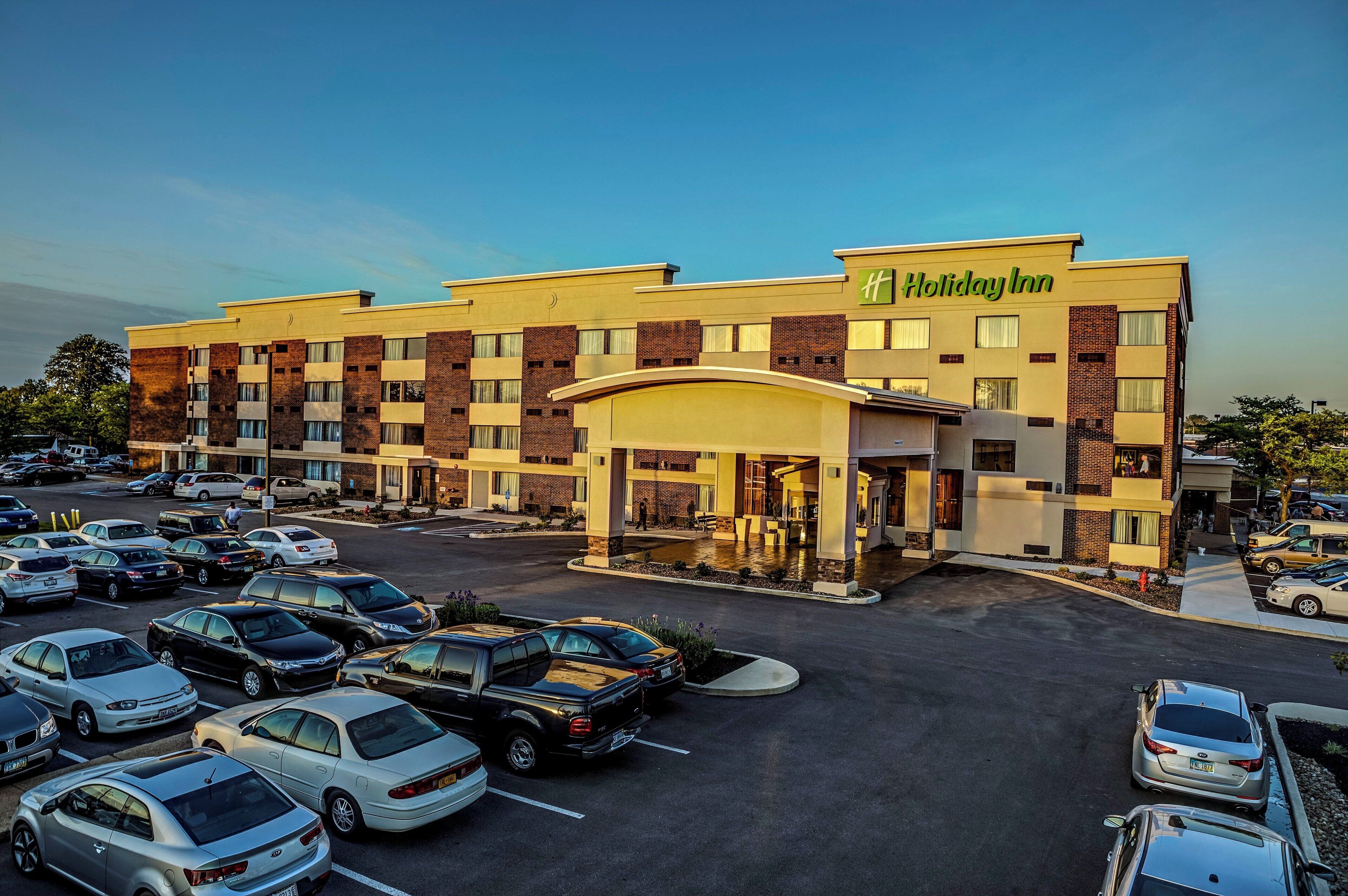 A Holiday Inn hotel with a parking lot filled with cars.