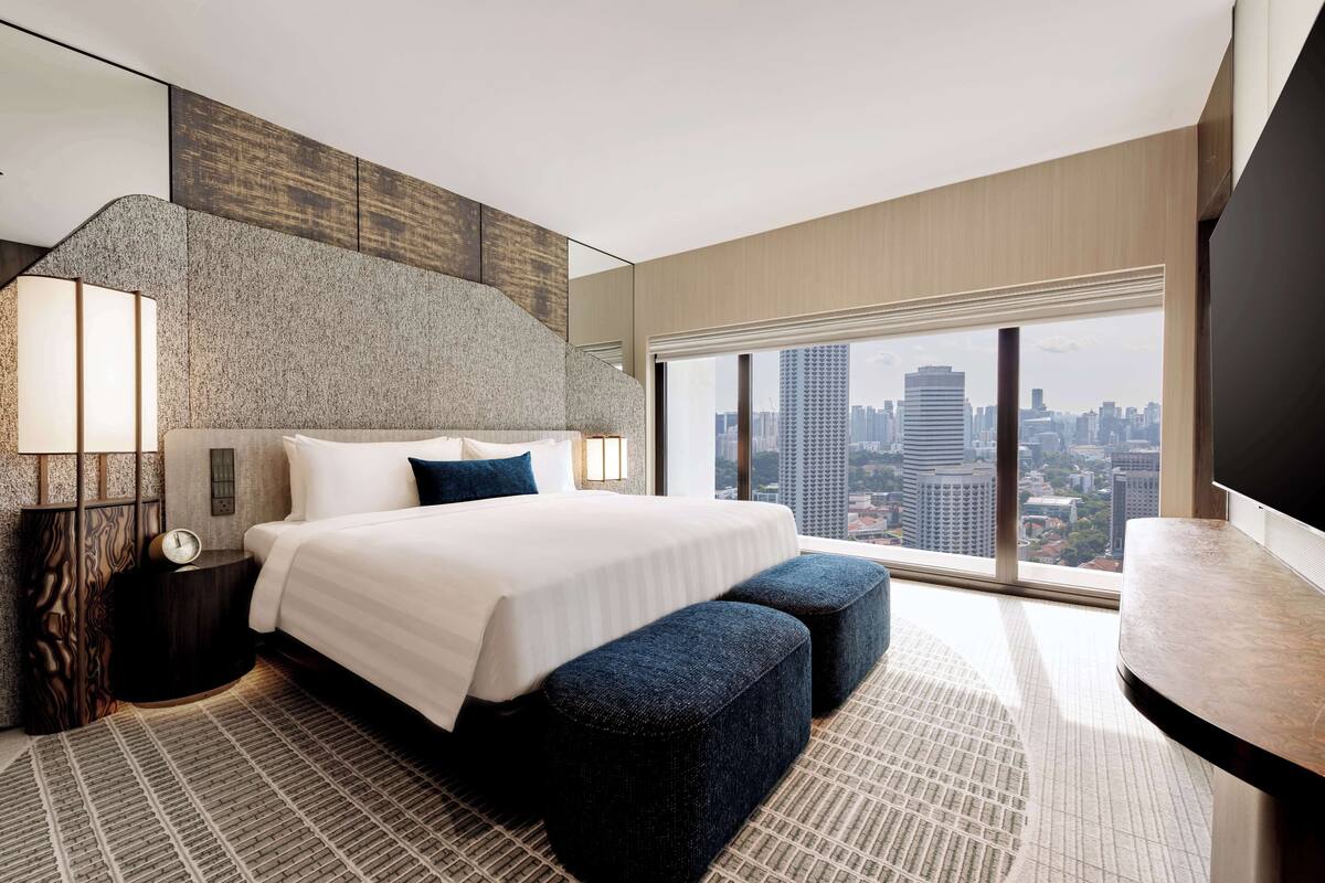 Una habitación de hotel moderna con una cama grande, vistas a la ciudad y un televisor de pantalla plana.